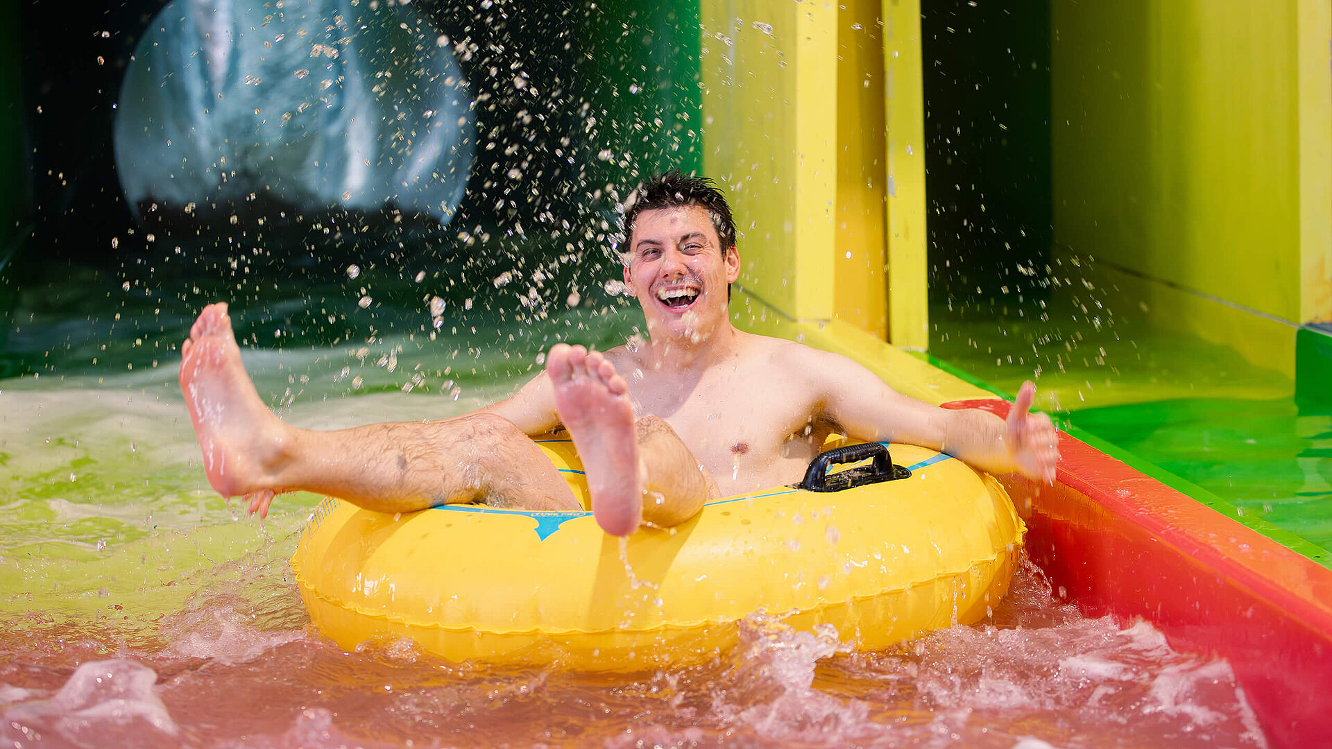 man on rubber ring riding water slide